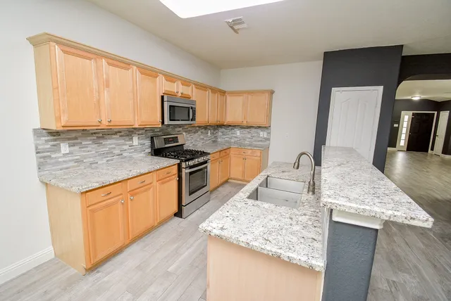 a kitchen with stainless steel appliances granite countertop a sink stove and refrigerator