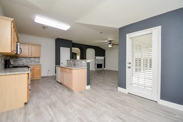 a large kitchen with a lot of counter space and wooden floor