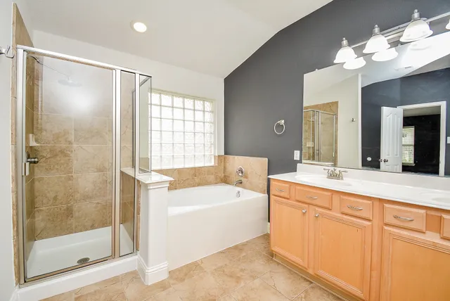 a spacious bathroom with a tub sink shower and mirror