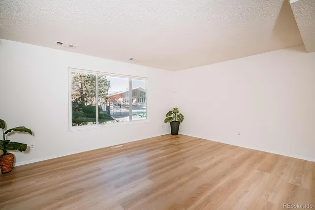 a view of an empty room with a window and wooden floor
