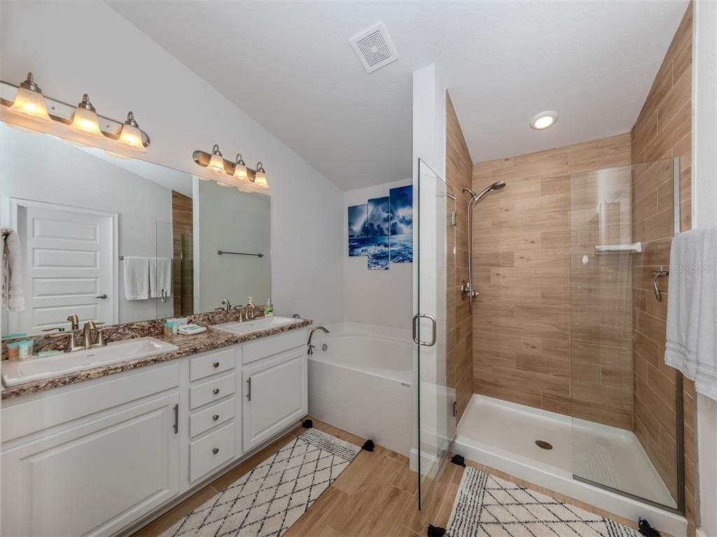 1190 Euclid Road Venice, FL 34293 - Photo 31 of 100 a bathroom with a double vanity sink a toilet a mirror and shower