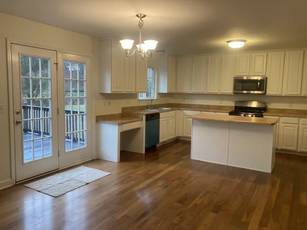 a kitchen with stainless steel appliances granite countertop a stove top oven a sink dishwasher a dining table and chairs with wooden floor