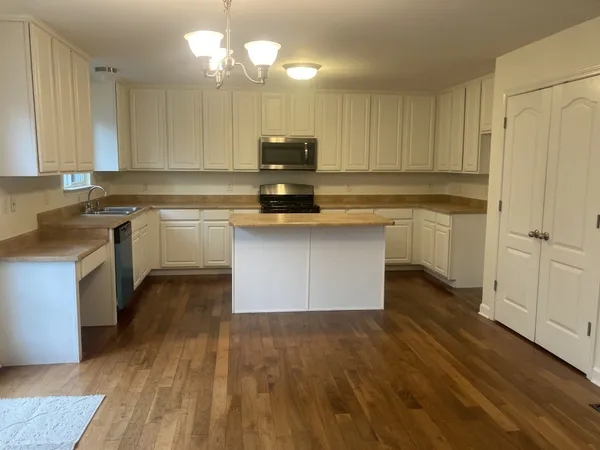 a kitchen with kitchen island granite countertop a sink cabinets and wooden floor