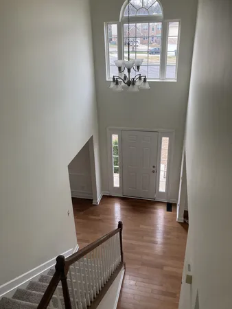 a view of a hallway with wooden floor and chandelier
