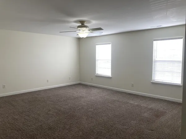 an empty room with a window and a chandelier fan