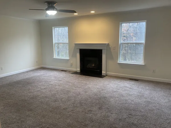 an empty room with windows and fireplace