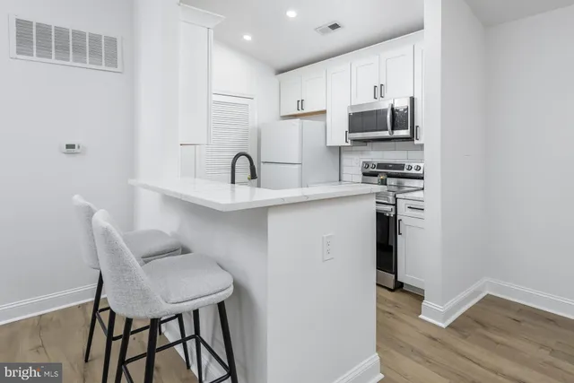 a kitchen with stainless steel appliances granite countertop a sink a stove a microwave a dining table and chairs