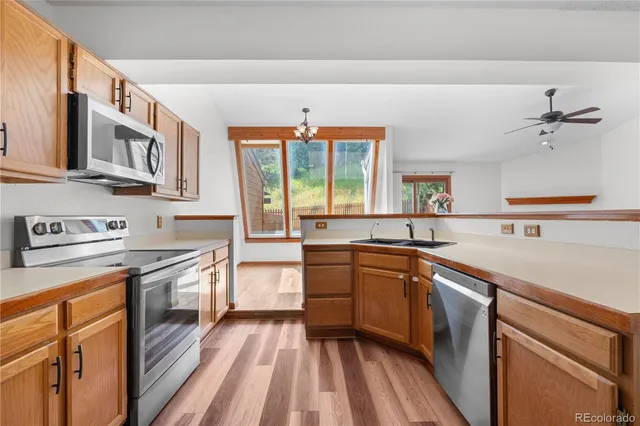 a kitchen with stainless steel appliances granite countertop a stove a sink dishwasher and white cabinets with wooden floor