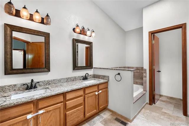 a bathroom with a granite countertop double vanity sink and a mirror