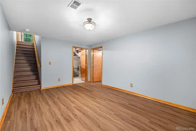 a view of an empty room with wooden floor and stairs