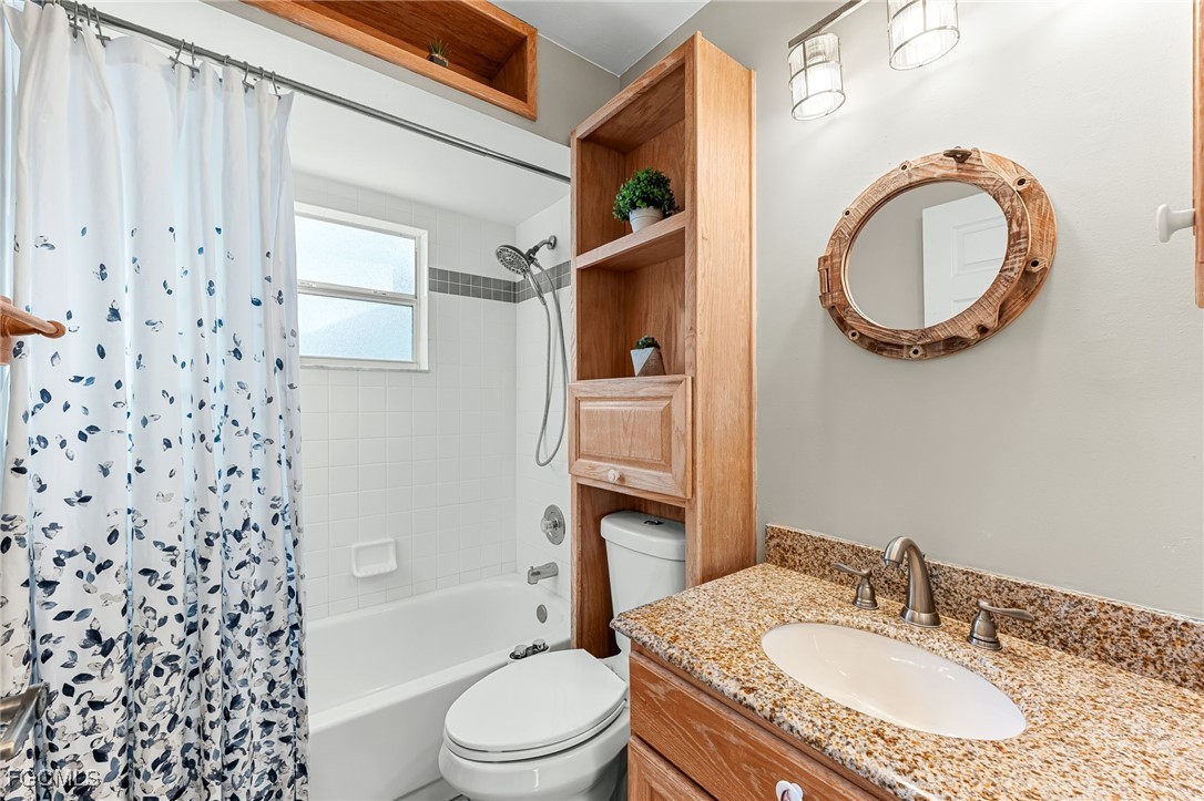 8468 Grove Road Fort Myers, FL 33967 - Photo 17 of 24 a bathroom with a granite countertop toilet a sink and a mirror
