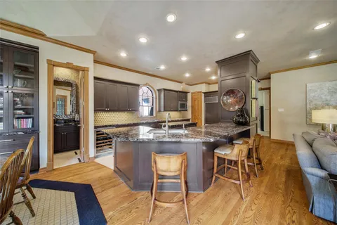 a kitchen with granite countertop kitchen island stainless steel appliances a sink and a refrigerator