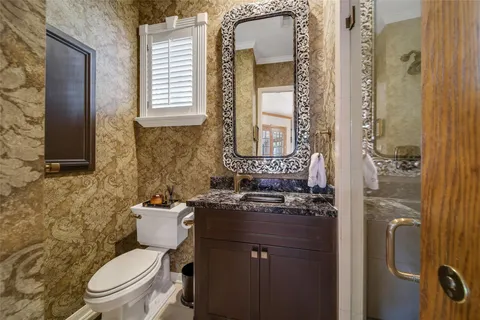 a bathroom with a granite countertop toilet sink and mirror