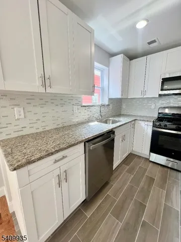 a kitchen with stainless steel appliances granite countertop a sink stove and cabinets