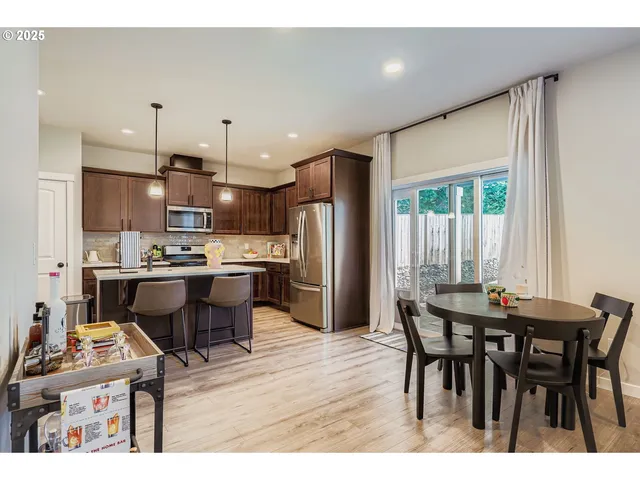a open kitchen with stainless steel appliances kitchen island granite countertop a dining table chairs and white cabinets