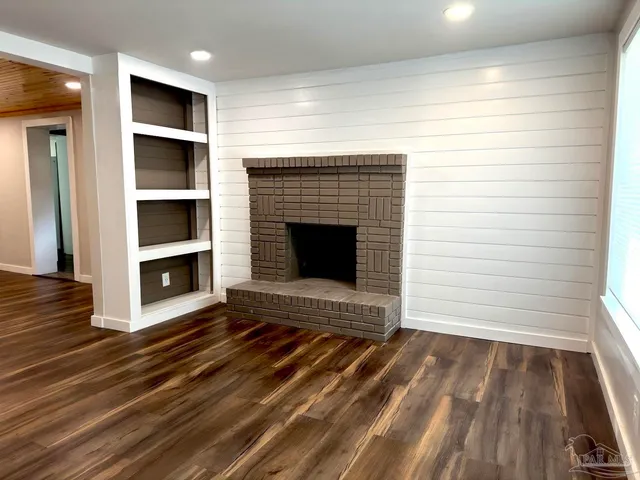 an empty room with wooden floor a fireplace and windows