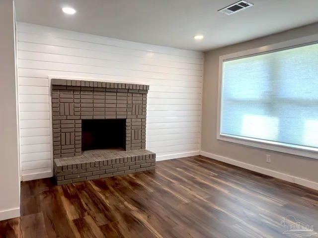 a view of empty room with wooden floor and fireplace