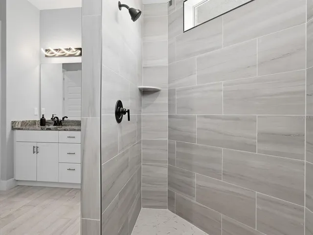 a bathroom with a granite countertop shower a sink and mirror