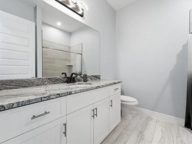 a bathroom with a granite countertop sink a toilet and a mirror