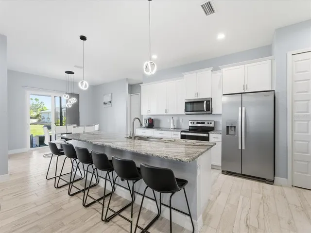 a kitchen with stainless steel appliances a dining table chairs stove refrigerator and microwave