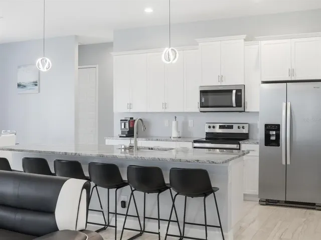 a kitchen with stainless steel appliances granite countertop a stove a sink dishwasher a refrigerator with a dining table and chairs