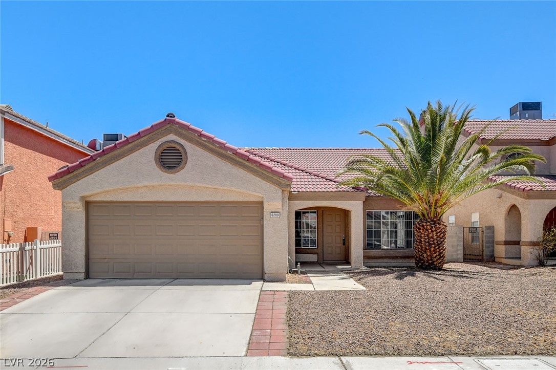 6209 Warm River Road Las Vegas, NV 89108 - Photo 1 of 39 A single-story home featuring a garage and a vibrant palm tree in its arid-friendly front yard.
