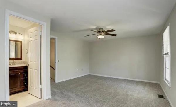 an empty room that has a chandelier fan and a window