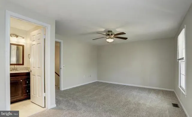an empty room that has a chandelier fan and a window