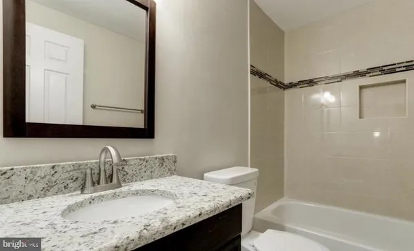 a bathroom with a granite countertop sink mirror and a bathtub
