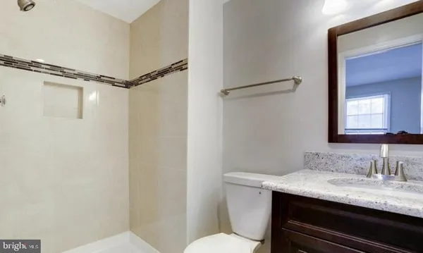 a bathroom with a granite countertop sink toilet and a mirror