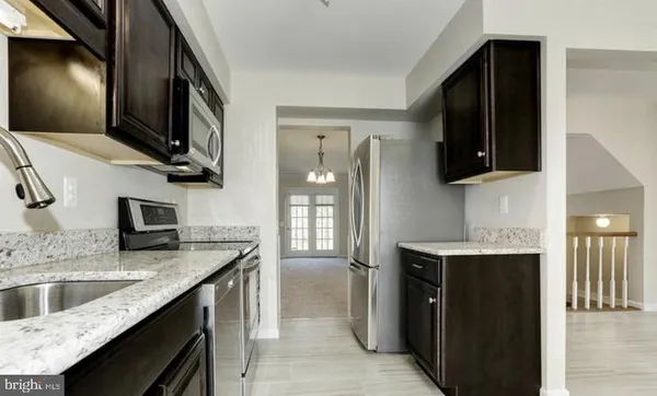 a kitchen with stainless steel appliances granite countertop a sink a stove and a refrigerator
