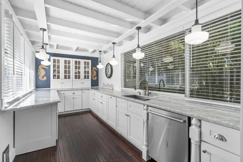 a kitchen with stainless steel appliances granite countertop a sink a stove and a wooden floors