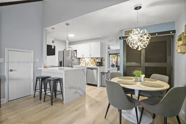 a kitchen with a dining table chairs stainless steel appliances and cabinets