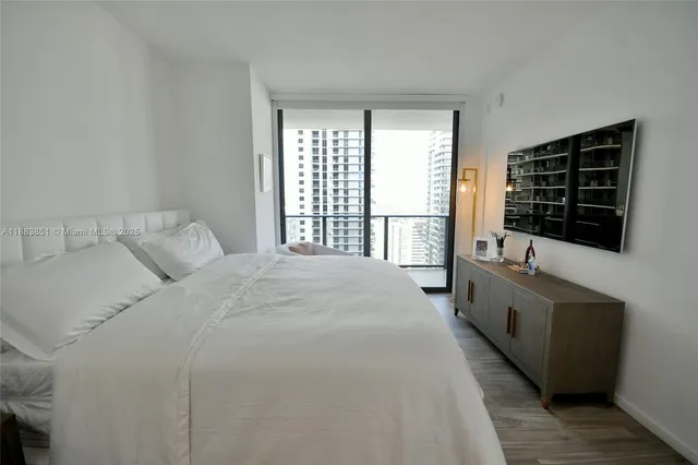 a large white bed sitting in a bedroom next to a window