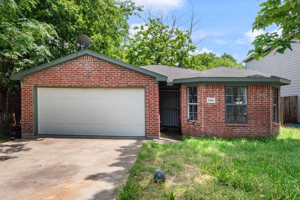 2526 Exeter Avenue Dallas, TX 75216 - Photo 6 of 19 Brick exterior featuring a two-car garage with a panel door, multiple window placements, and a covered entry