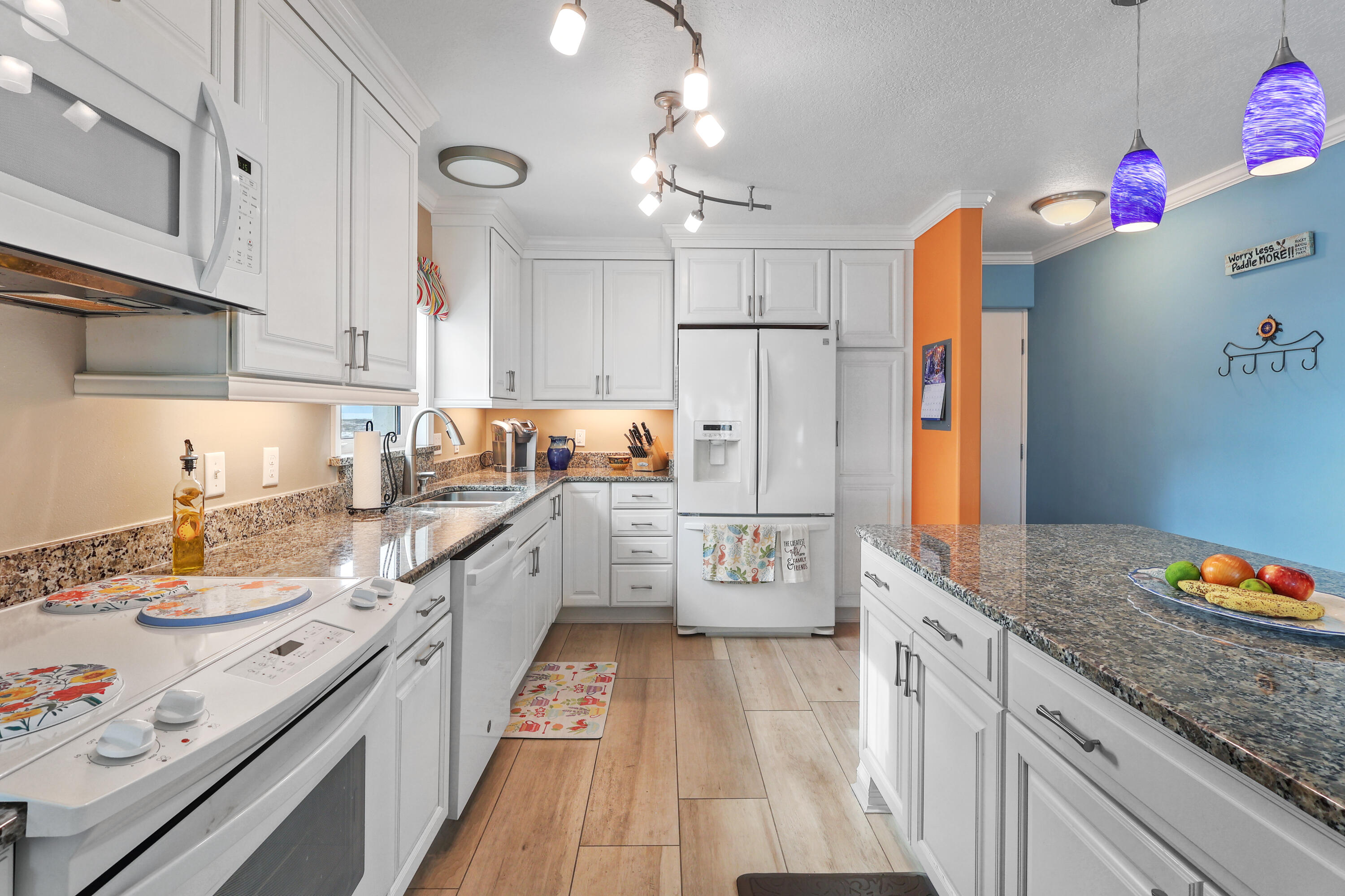 909 Santa Rosa Boulevard, Unit 229 Fort Walton Beach, FL 32548 - Photo 2 of 48 a kitchen with granite countertop a white refrigerator a sink dishwasher and white countertops with wooden floor