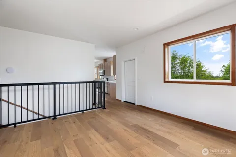 a view of an empty room with window and wooden floor
