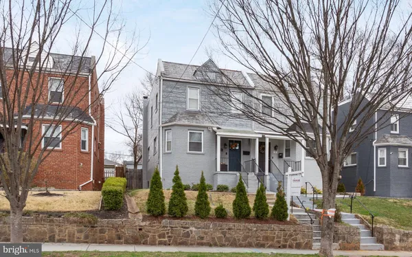 a view of a white house with a large tree