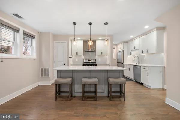a kitchen with stainless steel appliances granite countertop a table chairs sink and cabinets