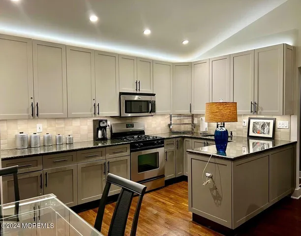 a kitchen with granite countertop a sink cabinets and stainless steel appliances