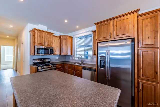 a kitchen with stainless steel appliances granite countertop a refrigerator a stove top oven a sink and dishwasher