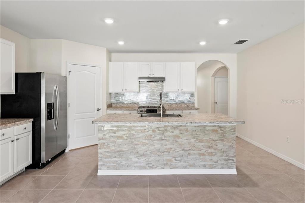 205 Old Mill Pond Road Palm Harbor, FL 34683 - Photo 17 of 57 a large kitchen with stainless steel appliances kitchen island granite countertop a refrigerator and a stove top oven