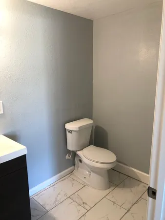 a white toilet sitting next to a white wall