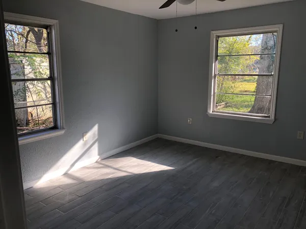 an empty room with wooden floor and windows