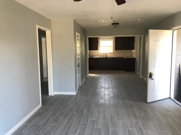 a view of kitchen and empty room with wooden floor