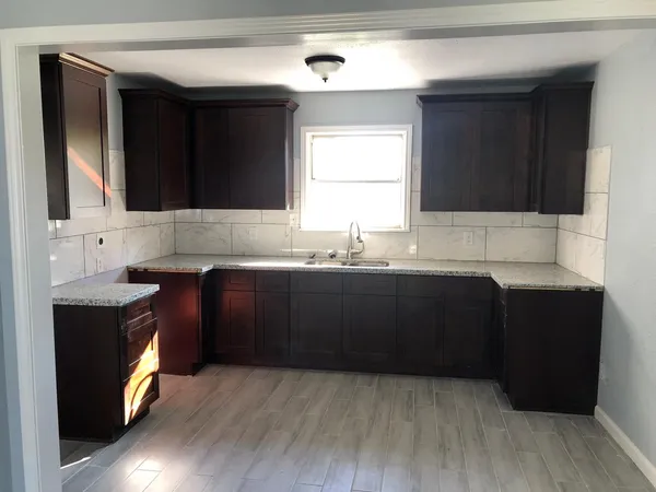 a kitchen with granite countertop a sink cabinets and wooden floor