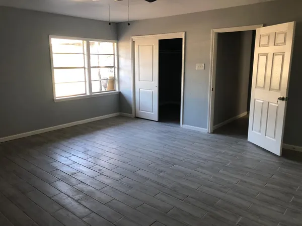 an empty room with wooden floor and windows