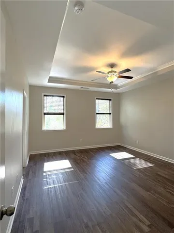 an empty room with wooden floor mirror and windows