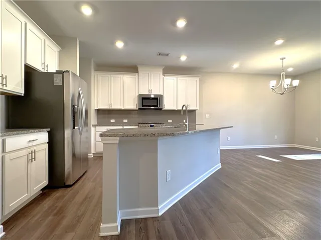 a kitchen with kitchen island granite countertop a sink cabinets and stainless steel appliances