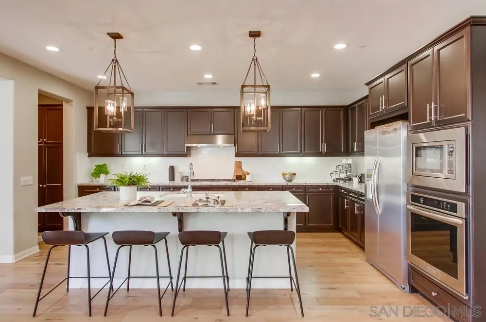 15559 Tanner Ridge Road San Diego, CA 92127 - Photo 5 of 25 a kitchen with stainless steel appliances granite countertop a stove top oven a refrigerator a sink and chairs